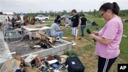 Carla Arendal looks at some jewelry she salvaged from her home after a tornado destroyed the building in Vilonia, Arkansas, April 26, 2011