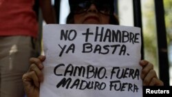 Seorang perempuan memegang poster "Tidak ada lagi kelaparan. Stop. Perubahan. Mundur Maduro, Mundur," merujuk ke Presiden Nicolas Maduro, dalam sebuah pawai kelompok-kelompok oposisi di Caracas, Venezuela, 17 Maret 2018. 