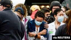 A woman consoles a King Soopers pharmacy technician after a shooting at the grocery store in Boulder, Colorado, March 22, 2021. 