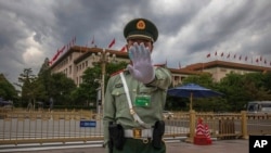 FILE - A Chinese People's Liberation Army soldier gestures to the photographer to stop taking photos in front of the Great Hall of the People, after the second plenary session of China's National People's Congress, in Beijing, May 25, 2020.