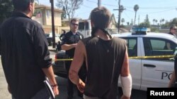 Polisi berbicara dengan korban penikaman dekat protes Klu Klux Klan di Anaheim, California, 27 Februari 2016. Setidaknya tiga orang ditikam, satu di antaranya luka parah, ketika anggota KKK dan kelompok kontra-demonstran bentrok.