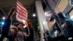 A protester stands facing police officers at an entrance of Terminal 4 at John F. Kennedy International Airport in New York, Jan. 28, 2017, after earlier in the day two Iraqi refugees were detained while trying to enter the country.