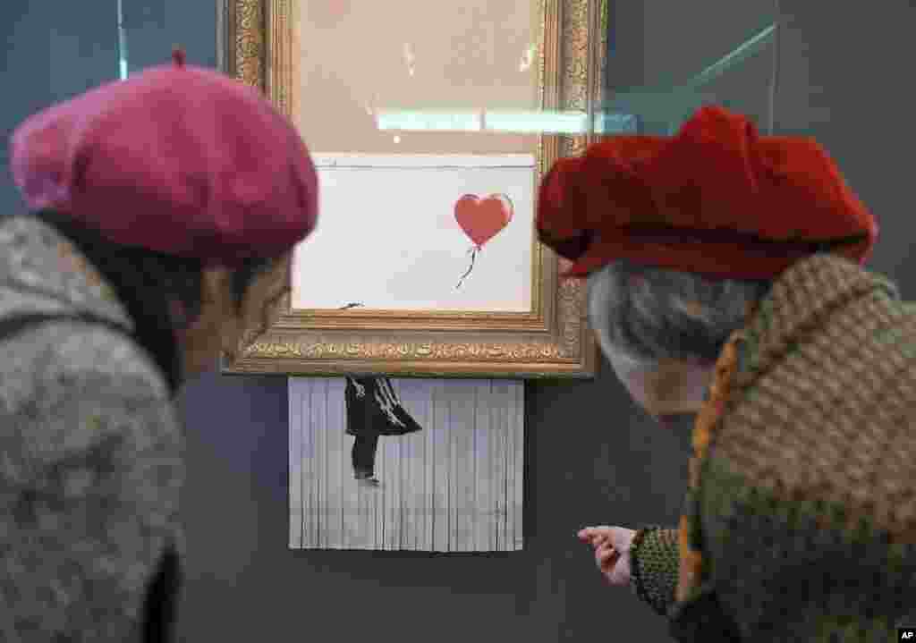 People look at the shredded Banksy painting "Love is in the Bin,"at the Museum Frieder Burda in Baden-Baden, where the work will be on display from Feb. 5 to March 3, 2019.