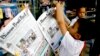 A Cambodian boy hangs up copies of the English-language newspaper, Phnom Penh Post, at the newsstand in Phnom Penh, file photo. 