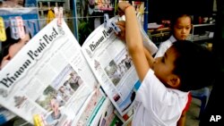 A Cambodian boy hangs up copies of the English-language newspaper, Phnom Penh Post, at the newsstand in Phnom Penh, file photo. 