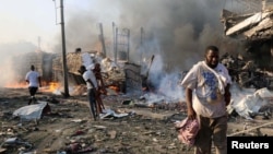Civilians walk at the scene of an explosion in KM4 street in the Hodan district of Mogadishu, Somalia October 14, 2017. REUTERS/Feisal Omar