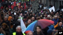 People march under rain during a demonstration in support of migrant people seeking to enter Europe, in Brussels, Saturday, Jan. 12, 2019.