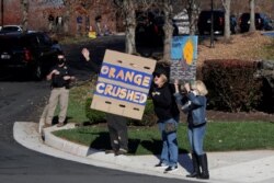 Supporters of President-Elect Joe Biden display signs of protest as the motorcade of U.S. President Donald Trump arrives at the Trump National Golf Club in Sterling, Virginia, Nov. 8, 2020.