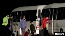 Warga Australia yang dievakuasi dari kota Wuhan, menuju bus yang akan membawa mereka ke tempat enampungan sementara setibanya di bandara Pulau Christmas, Australia, 6 Februari 2020. 