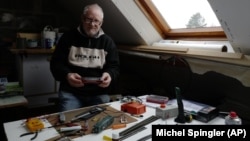 Guy Warein, a 70-year-old retiree, works on model trains in his home in Richebourg, northern France, Wednesday, Jan. 27, 2021. (AP Photo/Michel Spingler)
