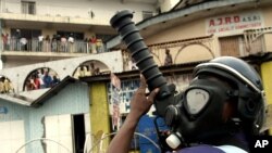 Des policiers couverts de masque lancent des gaz lacrymogènes lors des affrontements avec des manifestants opposés au référendum constitutionnel à Kinshasa, 16 décembre 2005.