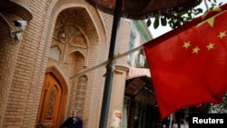Ilustrasi - Seorang pria tua terlihat di belakang bendera nasional China di Kota Tua Kashgar di Daerah Otonomi Uyghur, Xinjiang, China, 6 September 2018. (REUTERS/Thomas Peter)