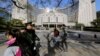 People walk past the headquarters of the People's Bank of China as two police officials patrol the area in Beijing Nov. 20, 2013. 