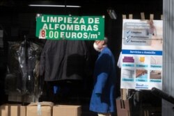 A man works in a dry-cleaners with sign advertising carpet cleaning, centre, in Madrid, Spain, May 4, 2020.