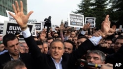 Ekrem Dumanli, editor-in-chief of Zaman newspaper, salutes cheering supporters as he is detained outside his office in Istanbul, Turkey, Dec. 14, 2014. 