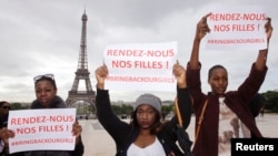 Women hold placards which read, "Bring back our girls", during a demonstration near the Eiffel Tower in Paris, May 13, 2014.