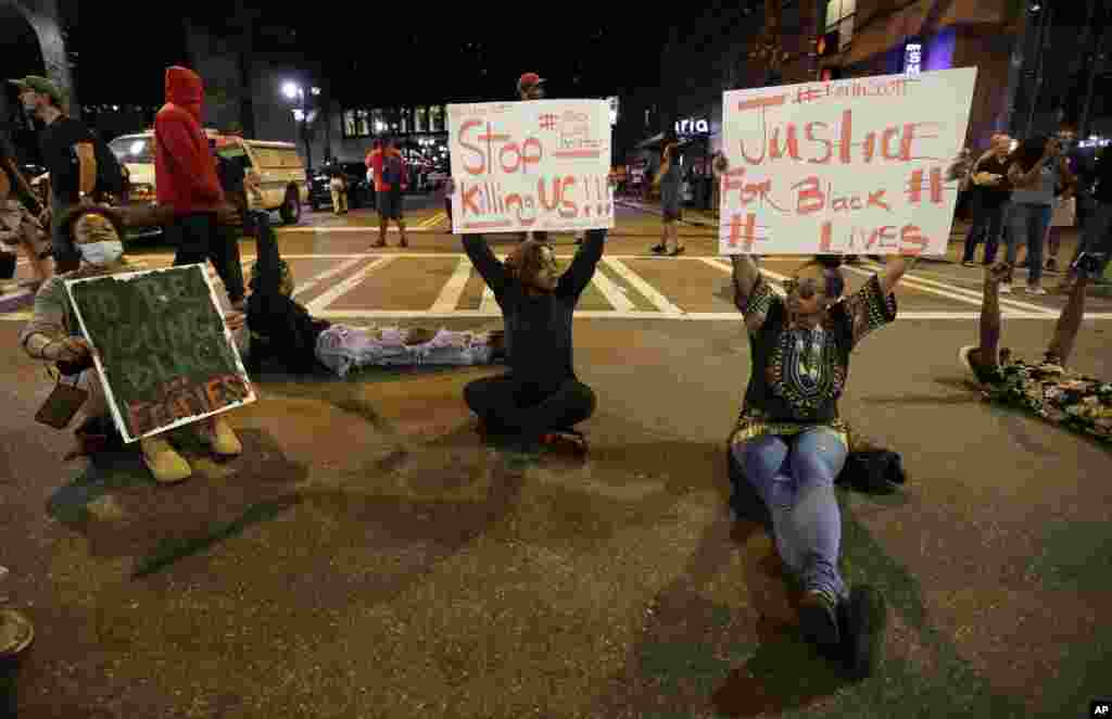 Demonstrators sit on a street during a protest of Tuesday's fatal police shooting of Keith Lamont Scott in Charlotte, N.C., Sept. 21, 2016. Protesters rushed police in riot gear at a downtown Charlotte hotel and officers have fired tear gas to disperse th