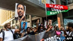 People raise their fists and hold signs and a banner as they march during an event in remembrance of George Floyd in Minneapolis, Minnesota, on May 23, 2021. 