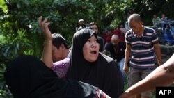 FILE - A woman calls out to her relatives after identifying bodies dumped off a cliff along the highway leading to Marawi on the southern island of Mindanao on May 28, 2017. 