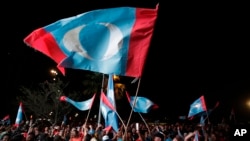 អ្នក​គាំទ្រ​គណបក្ស​ប្រឆាំង​អបអរ​ និង​គ្រវី​ទង់ជាតិ​បក្ស​របស់​ពួកគេ បន្ទាប់​ពី​លោក Mahathir Mohamad បាន​លើក​ឡើង​ពីជ័យជម្នះ​របស់​បក្ស​ប្រឆាំង​ឈ្នះ​ការបោះឆ្នោត​ជាតិ​ តាម​រយៈ​ការផ្សព្វផ្សាយ​តាម​ផ្ទាំង​ធំមួយ​នៅកន្លែង​សាធារណៈ​មួយ​ ក្នុងទីក្រុងគូឡាឡាំពួ ប្រទេស​ម៉ាឡេស៊ី កាល​ពី​ថ្ងៃ​ទី​៩ ខែ​ឧសភា​ ឆ្នាំ​២០១៨។ 