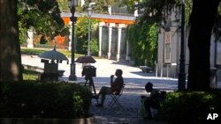 FILE - A portrait photographer waits for customers in the Paseo del Prado boulevard in Madrid, Spain, July 23, 2021. The city's tree-lined Paseo del Prado boulevard and the adjoining Retiro park have been added to UNESCO's World Heritage list. 