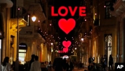 Lebanese citizens walk by Valentine's Day decorations, in downtown Beirut, Lebanon, Friday, Feb. 9, 2018. (AP Photo/Hussein Malla)
