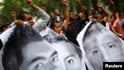 Para pedemo mengacungkan tinju sementara para kerabat dari 43 mahasiswa Sekolah Pelatihan Guru Ayotzinapa, memperingati 6 tahun hilangnya para pelajar itu di Mexico City, Sabtu, 26 September 2020. (Foto: Reuters)