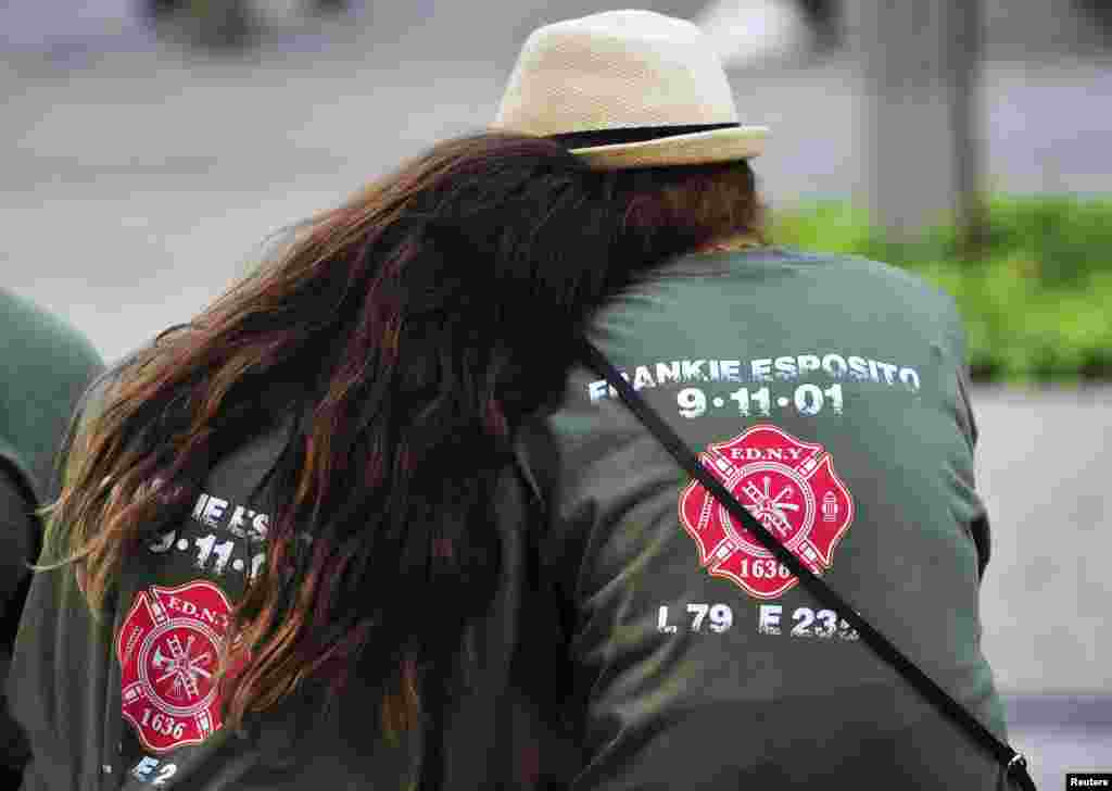 Two people with shirts commemorating New York City Fire Department firefighter Frankie Esposito sit at the south reflecting pool at the 9/11 Memorial during ceremonies marking the 12th anniversary of the attacks.