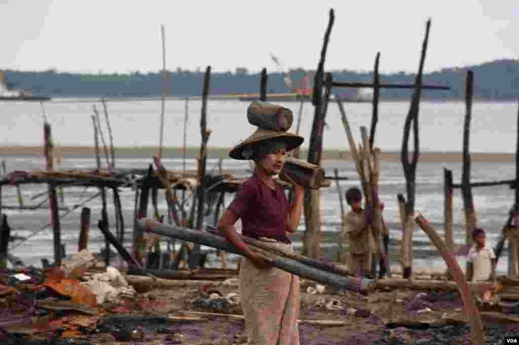 A woman balances scavenged wood in a burnt Muslim neighborhood, Kyauk Phyu, Rakhine State, Burma, November, 2012. (D. Schearf/VOA)