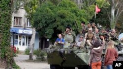 Warga melambai pada pemberontak pro-Rusia di atas kendaraan berlapis baja.