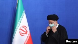 에브라힘 라이시 이란 대통령이 29일 테헤란에서 내외신 기자회견을 마친 뒤 국기 앞을 지나고 있다. 