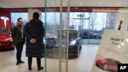 FILE - A sales staff chats with a customer at a Tesla store in Beijing, China, Monday, Jan. 7, 2019. 