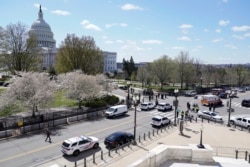 Police officers surround the scene after a car that crashed into a barrier on Capitol Hill on the Senate side of the U.S. Capitol in Washington, Friday, April 2, 2021. (AP Photo/J. Scott Applewhite)