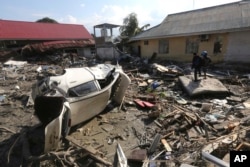 People survey the damage following a massive earthquake and tsunami at Talise beach in Palu, Central Sulawesi, Indonesia, Monday, Oct. 1, 2018.