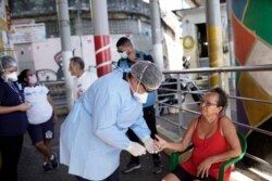 FILE - A city health worker takes a resident's blood sample, part of a program that aims to administer 20,000 COVID-19 tests in Rio de Janeiro's poor neighborhoods, at Morro da Providencia favela, Rio de Janeiro, Brazil, Sept. 3, 2020.