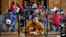 FILE - In this March 31, 2021, file photo, freshman Hugo Bautista eats lunch separated from classmates by plastic dividers at Wyandotte County High School in Kansas City, Kan., on the first day of in-person learning. (AP Photo/Charlie Riedel, File)