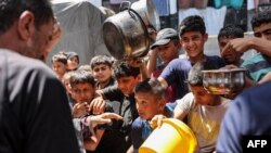 Anak-anak membawa panci saat antre untuk menerima bantuan makanan dari dapur di sekolah Abu Zeitun yang dikelola oleh Badan Bantuan dan Pekerjaan PBB untuk Pengungsi Palestina (UNRWA) di kamp Jabalia di Jalur Gaza utara (13/6) lalu. 