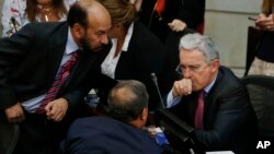 Former President Alvaro Uribe, right, talks to Senator of the Democratic Center Alfredo Rangel during a Senate session in Bogota, Colombia, Monday, Oct. 3, 2016. Colombians rejected a peace deal with leftist rebels in a national referendum Sunday. Uribe led the opposition.