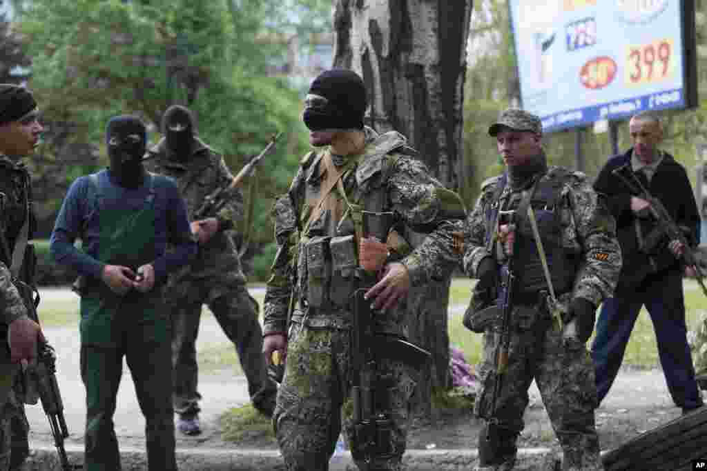 Pro-Russian gunmen listen to instructions from their commander, center, behind barricades in Slovyansk, eastern Ukraine, Friday, May 2, 2014.