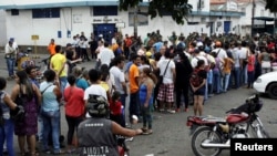 FILE - People make a line in front of Venezuelan National Guards as they wait to try to cross the border to Colombia over the Francisco de Paula Santander international bridge in Urena, Venezuela, Dec. 18, 2016.