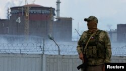 რუსული შეიარაღებული ძალების წარმომადგენელი, ზაპორიჟიის ატომური ელექტროსადგურის ფონზე.