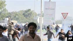 Riot police chase Bahraini demonstrators as they disperse a protest with tear gas in the village of Duraz, Bahrain, outside the capital of Manama, February 14, 2011