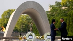 U.S. President Barack Obama (R) puts his arm around Japanese Prime Minister Shinzo Abe after they laid wreaths in front of a cenotaph at Hiroshima Peace Memorial Park in Hiroshima, Japan. May 27, 2016.