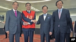 Chinese Vice Premier Li Keqiang (2nd L), wearing a floor trader's vest, poses with Hong Kong Stock Exchange Chairman Ronald Arculli (L), Chief Executive Charles Li (R) and Hong Kong Chief Executive Donald Tsang during his visit to the Hong Kong Stock Exch