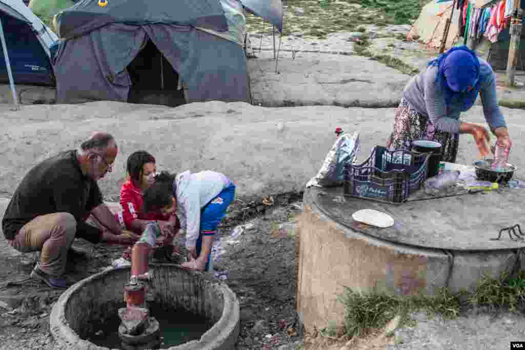 A family wash up as the light fades over Idomeni. While some have tried to cross the border using smugglers, others who spoke to VOA said that having children meant they could not risk it, April 22, 2016. (J. Owens/VOA)