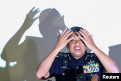 Malaysia's Royal Police Chief Khalid Abu Bakar demonstrates to the media during a news conference regarding the apparent assassination of Kim Jong Nam, the half-brother of the North Korean leader, at the Malaysian police headquarters in Kuala Lumpur, Malaysia, Feb. 22, 2017.