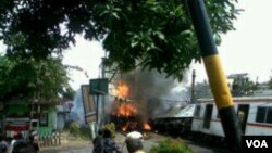 People watch a train burn after crashing in Jakarta, Dec. 9, 2013. (Andy Lala Waluyo for VOA)