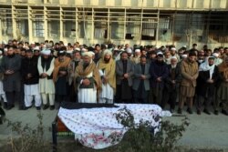 Villagers offer prayers over the coffin of Mohammad Yousuf Rasheed, executive director of the nongovernmental Free and Fair Election Forum of Afghanistan, during his funeral, in Kabul, Afghanistan, Dec. 23, 2020.