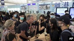 Putnici se raspravljaju sa demonstrantima dok pokušavaju da prođu kroz aerodromske odlazne gejtove, na međunarodnom aerodromu u Hong Kongu, 13. avgusta 2019.