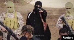 FILE - An Islamic State militant holds a gun while standing behind what are said to be Ethiopian Christians in Wilayat Fazzan, in this still image from an undated video made available on a social media website on April 19, 2015.